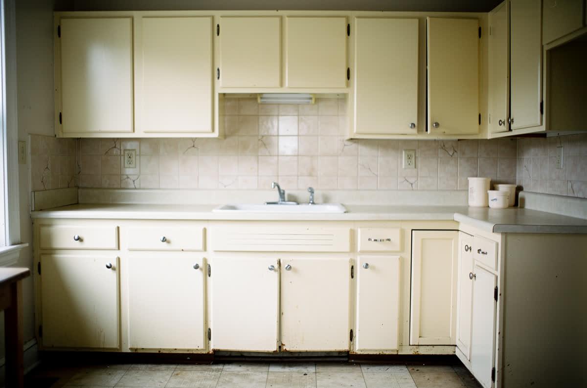 Kitchen with good bones but tired cosmetic finishes, photographed wide and evenly lit