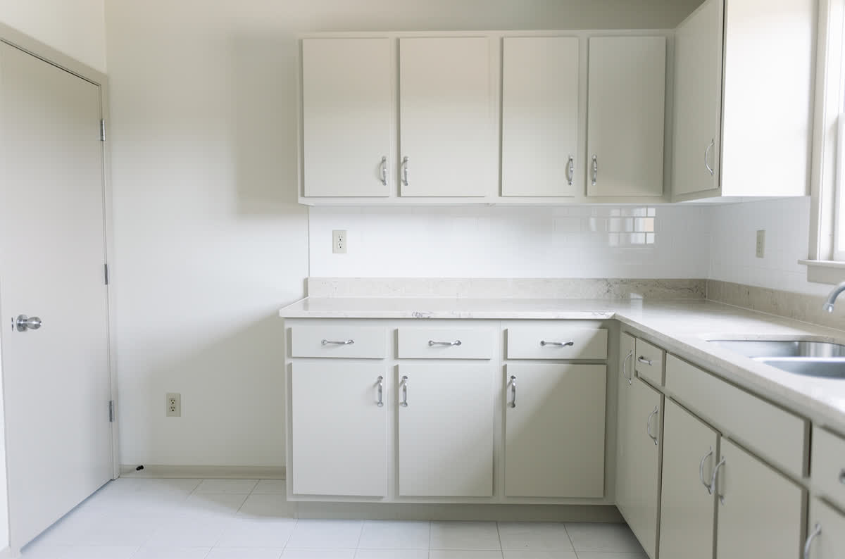 The same kitchen visualised with pale modern cabinets, light stone counters and a white tile backsplash