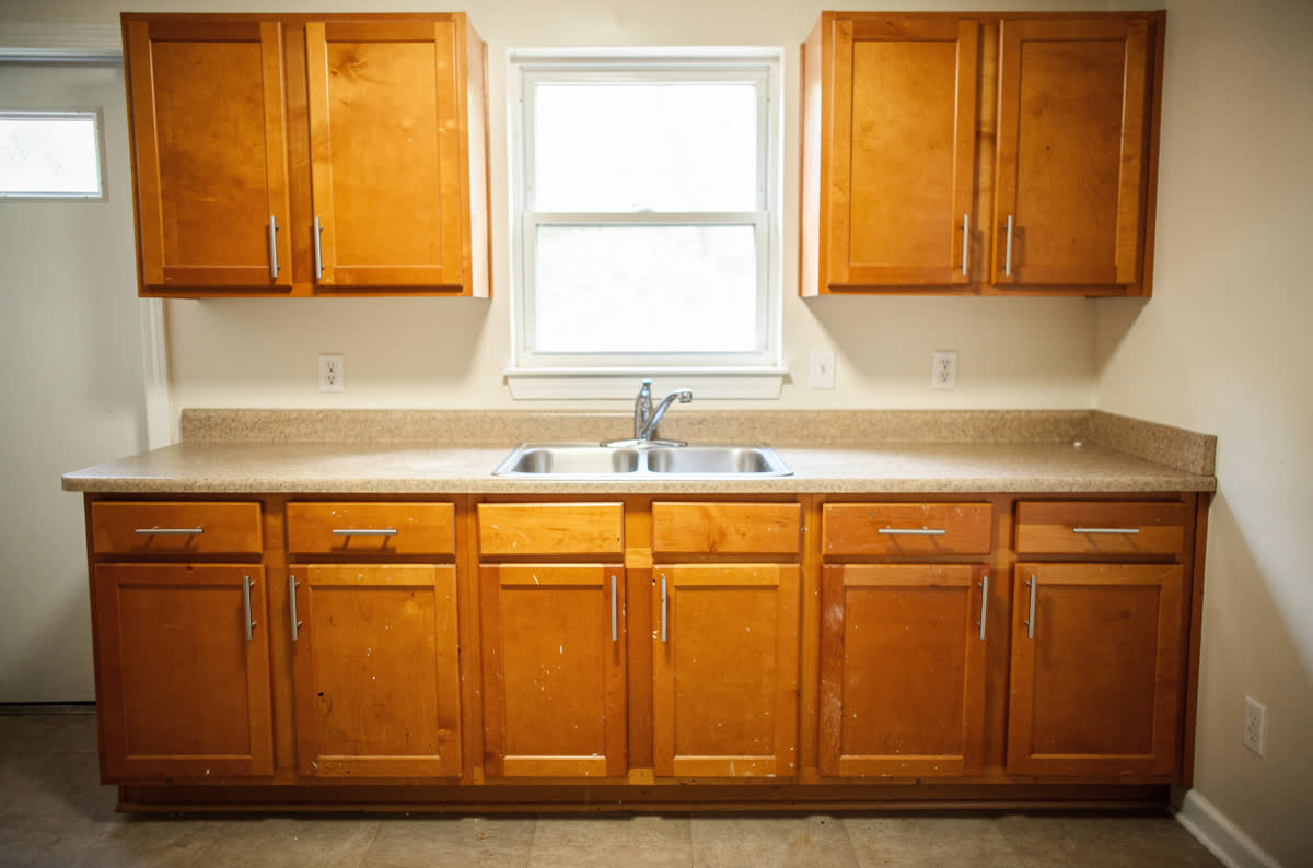Builder-grade kitchen with honey maple cabinets, speckled laminate counters and basic bar-pull hardware