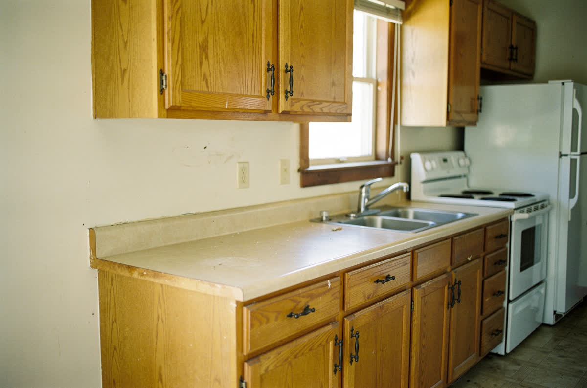 Tired kitchen with dated golden oak cabinets, old chrome faucet and no backsplash
