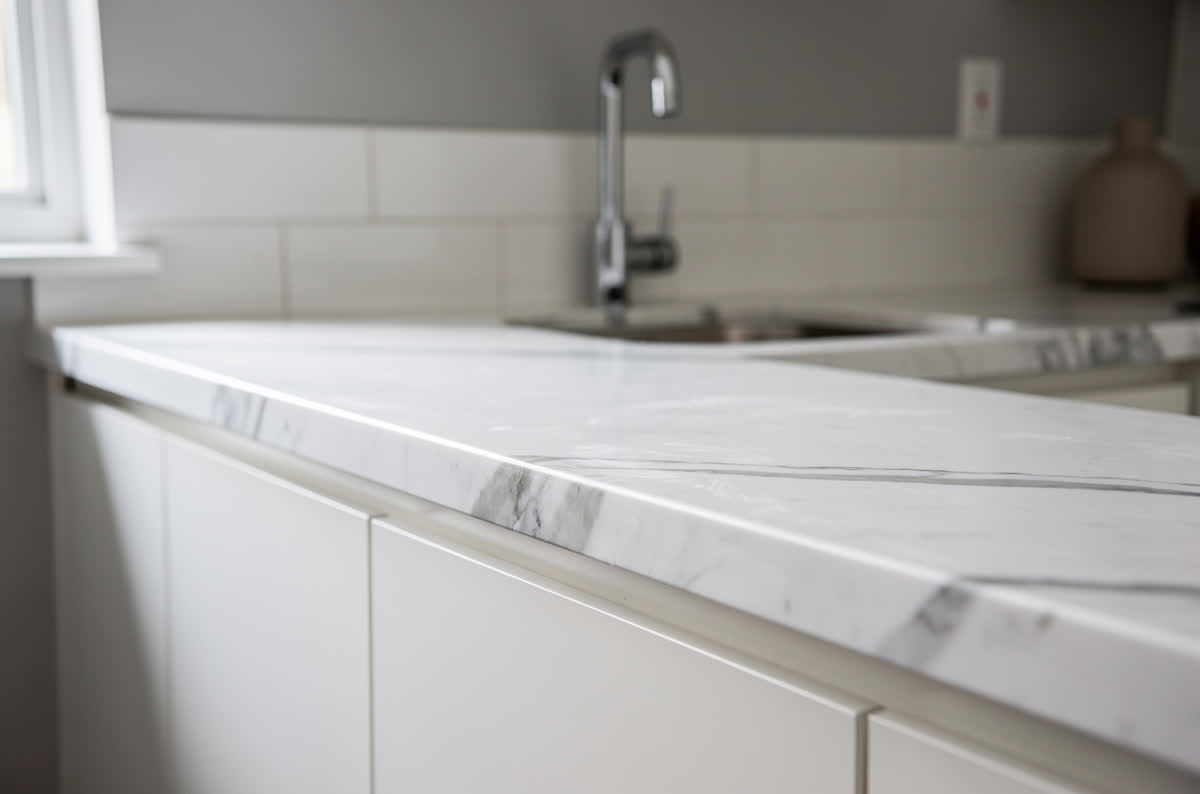 Marble-look laminate countertops in white with soft gray veining above plain white cabinets