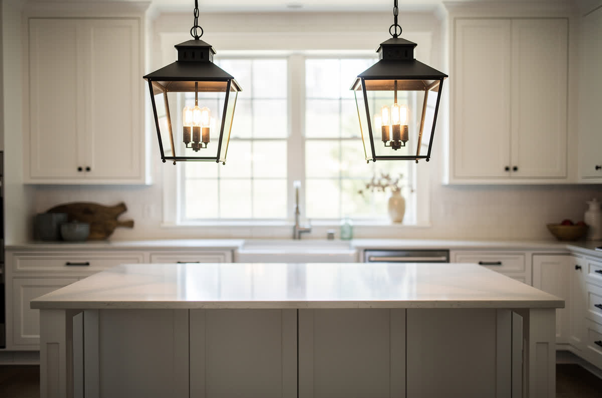 Two black lantern pendant lights with glass panels above a farmhouse island
