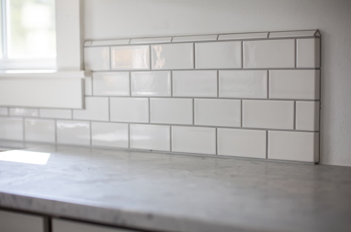 White subway tile backsplash laid in a brick pattern with soft gray grout lines