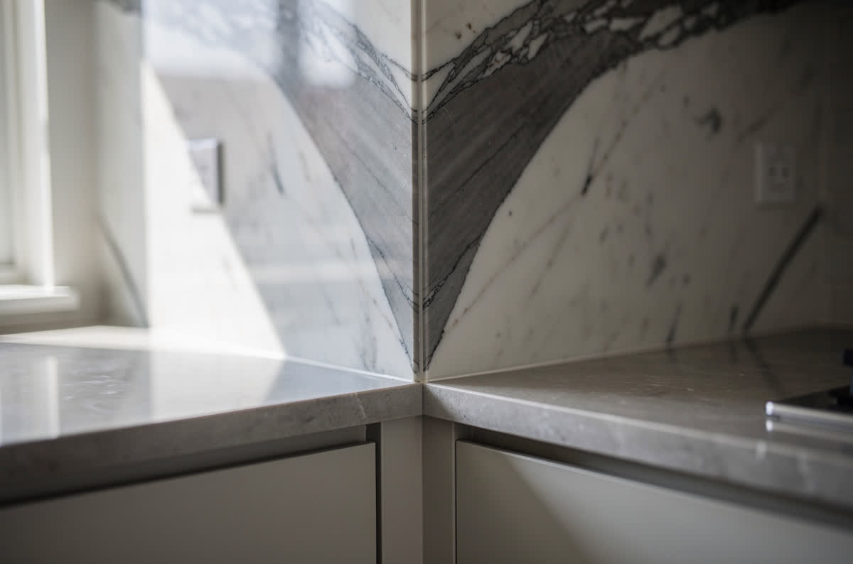 Bookmatched white marble slab with gray veining meeting a stone countertop