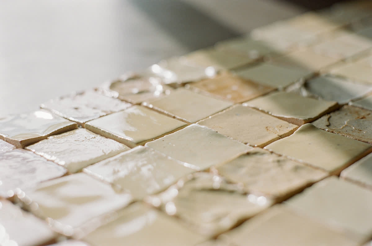 Glossy handmade zellige tile in warm cream, each tile catching the light differently