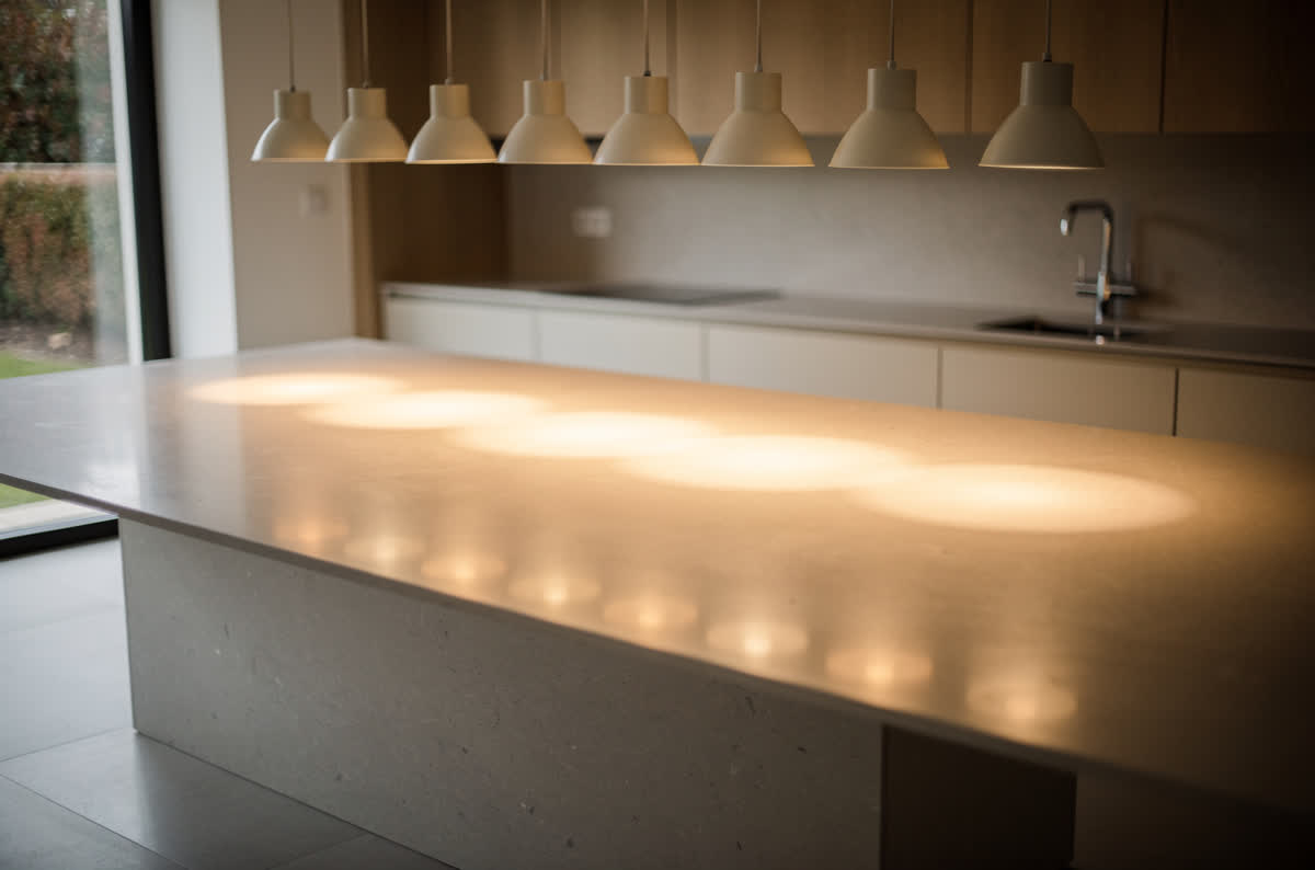 Kitchen island lit by evenly spaced pendants, their pools of warm light overlapping across the counter