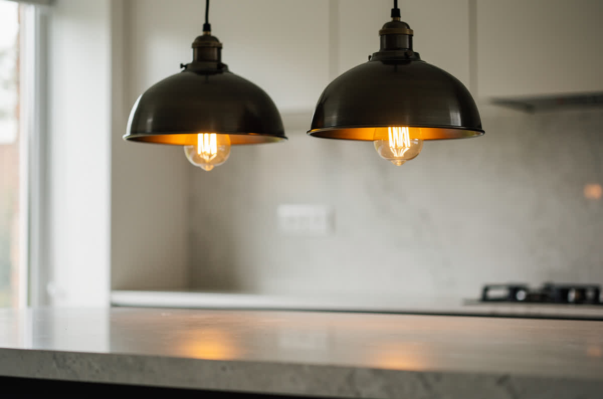Two industrial pendant lights with dark metal dome shades and exposed bulbs above a counter