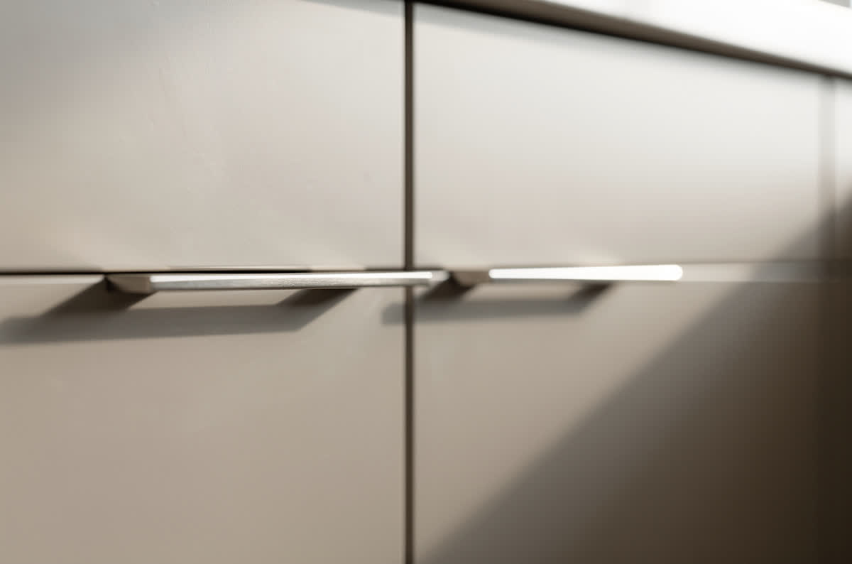 Slim geometric bar pulls on modern cabinet fronts, shown close up