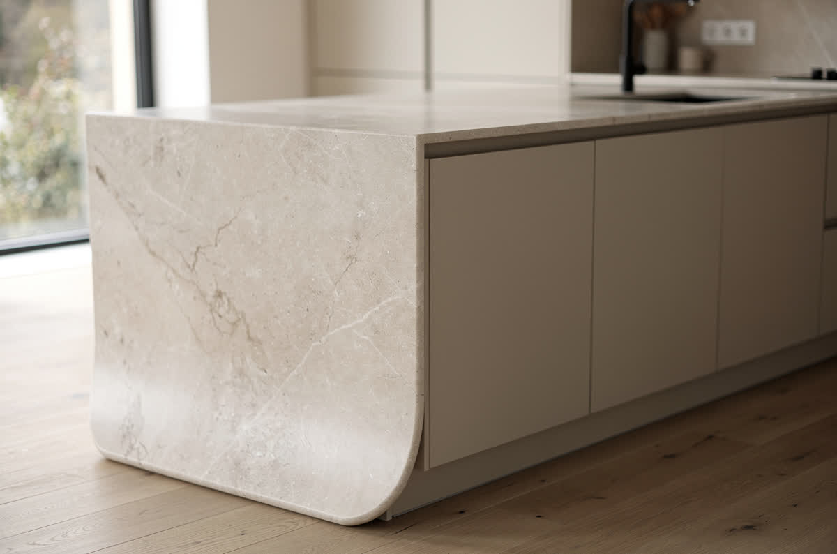 Island where the pale stone countertop turns and flows down the side to the floor