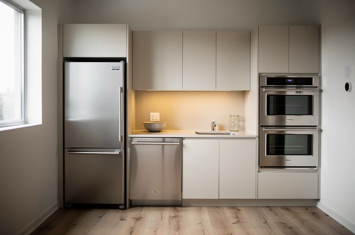 Small kitchen fitted with a narrow refrigerator, a drawer dishwasher and a compact wall oven