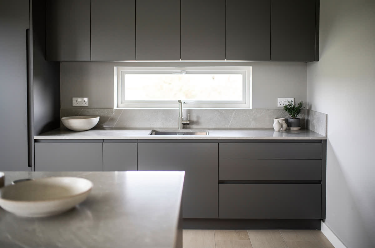 Small modern kitchen with flat-panel graphite cabinets and pale stone counters