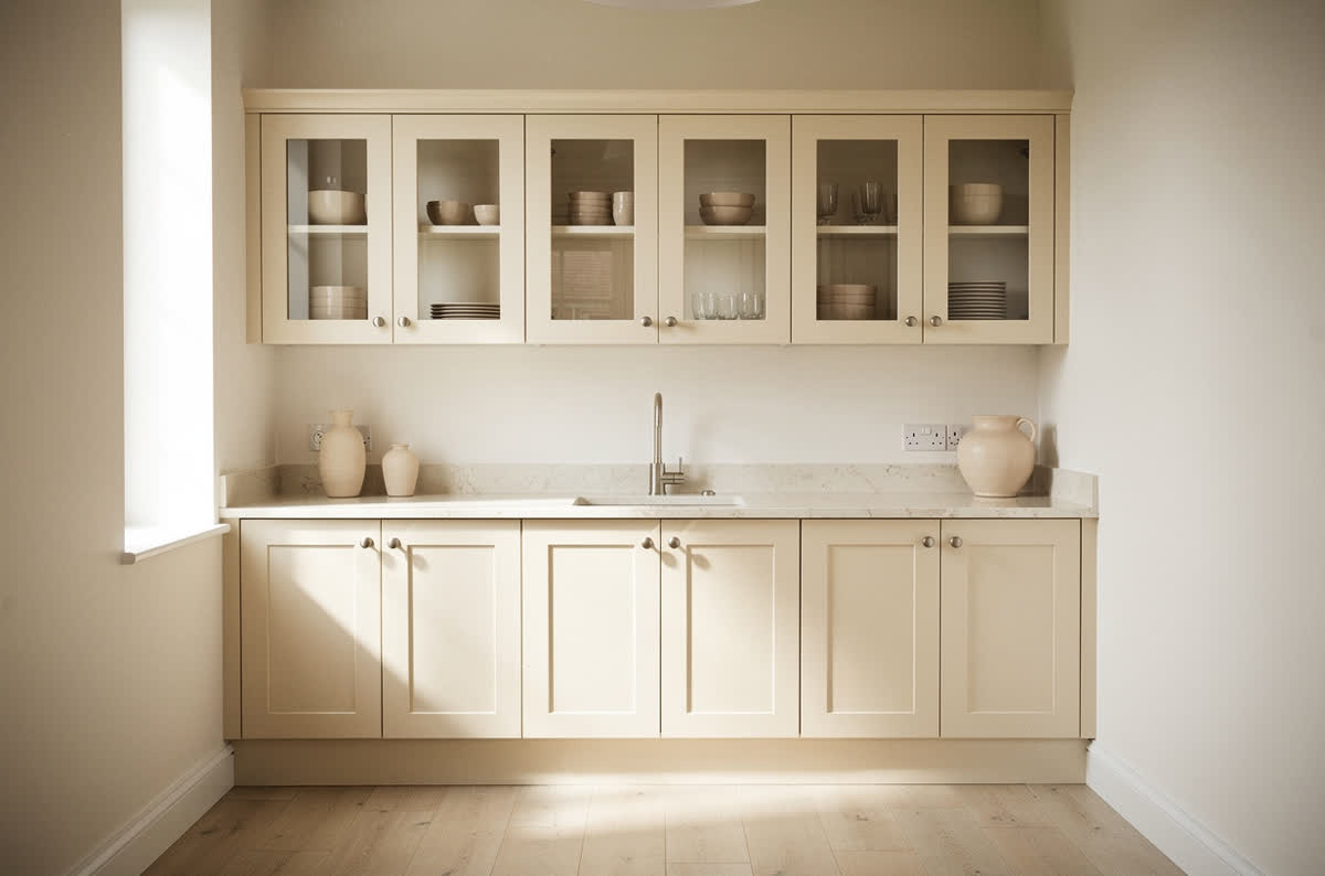 Small kitchen in an all-light palette with cream cabinets and glass-front upper doors