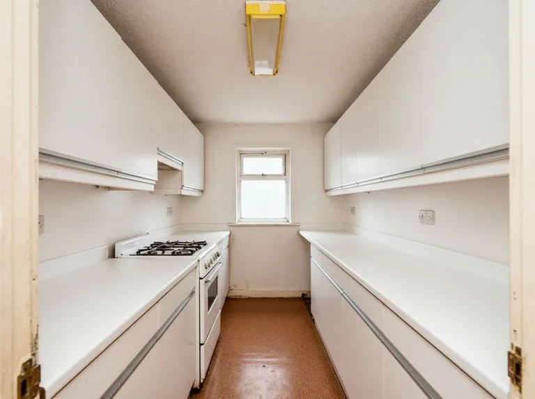 The same galley in plain white cabinets and white counters, with the walls painted out