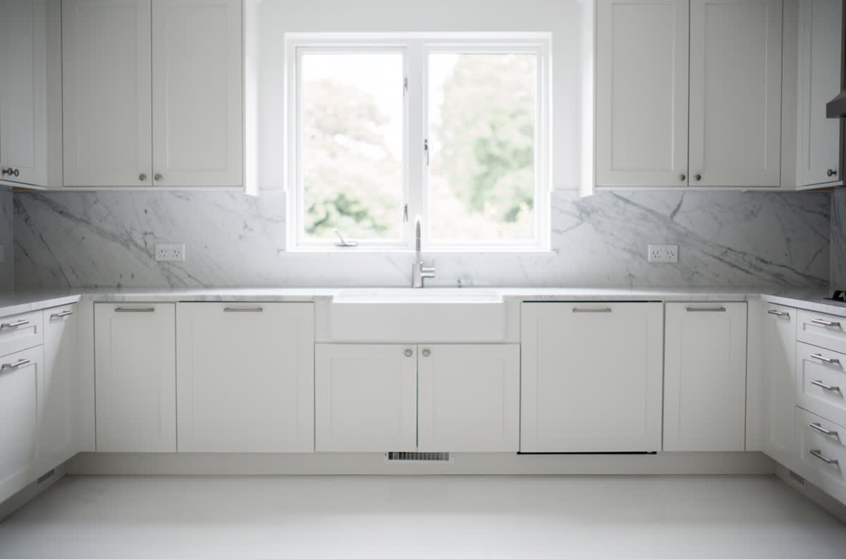 All-white kitchen with white cabinets, marble countertops and a marble backsplash