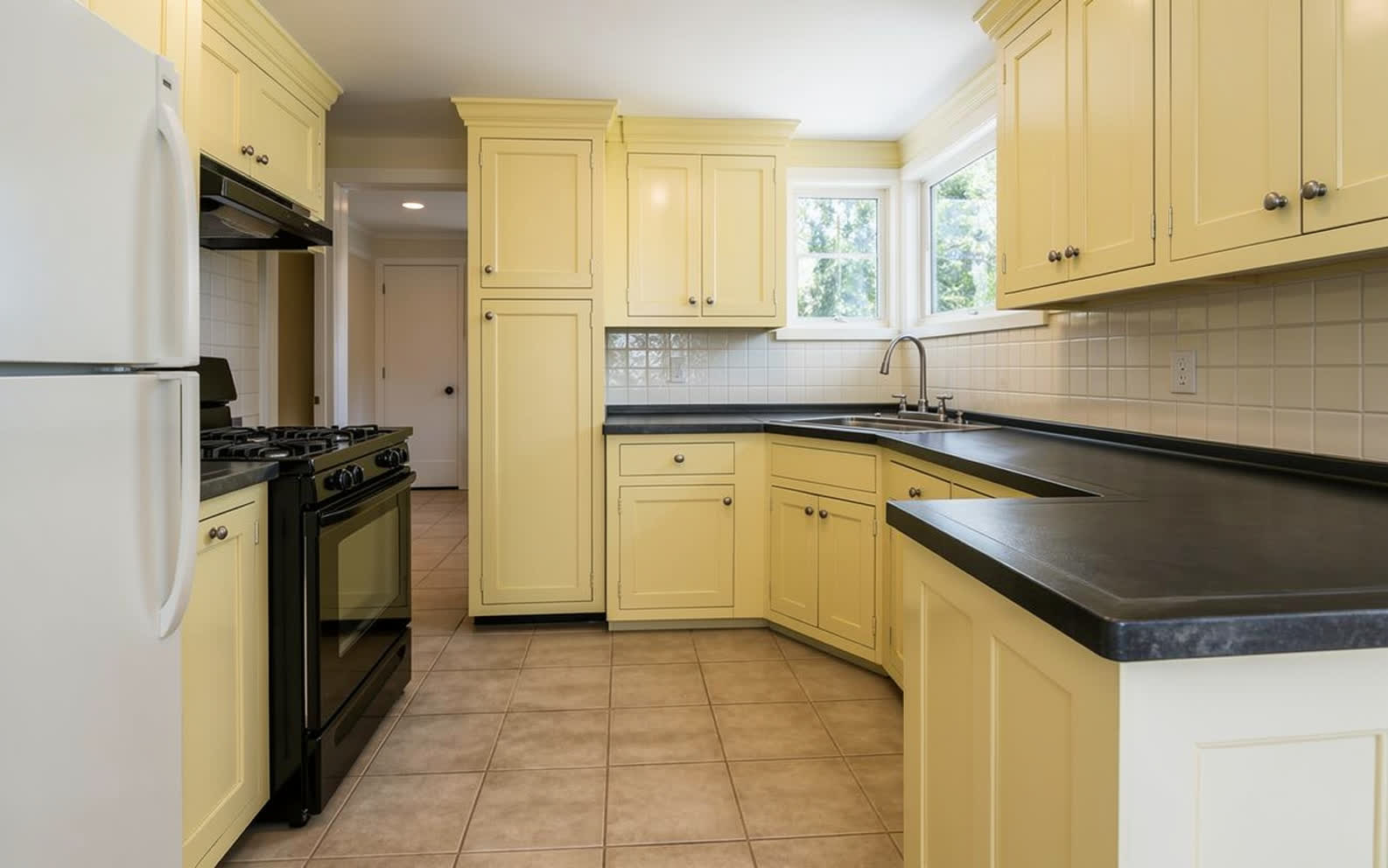The same kitchen with every door repainted soft butter yellow