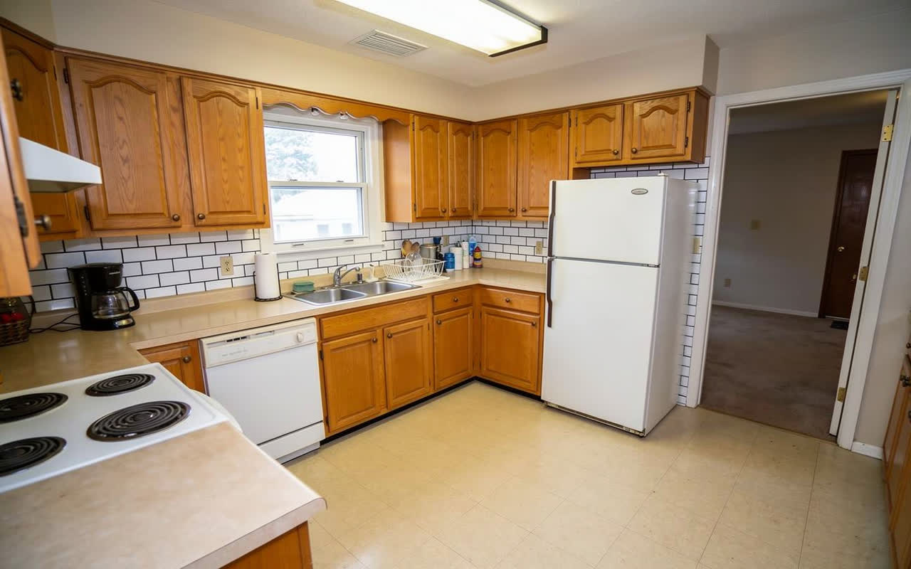 The same kitchen with glossy white subway tile and dark charcoal grout