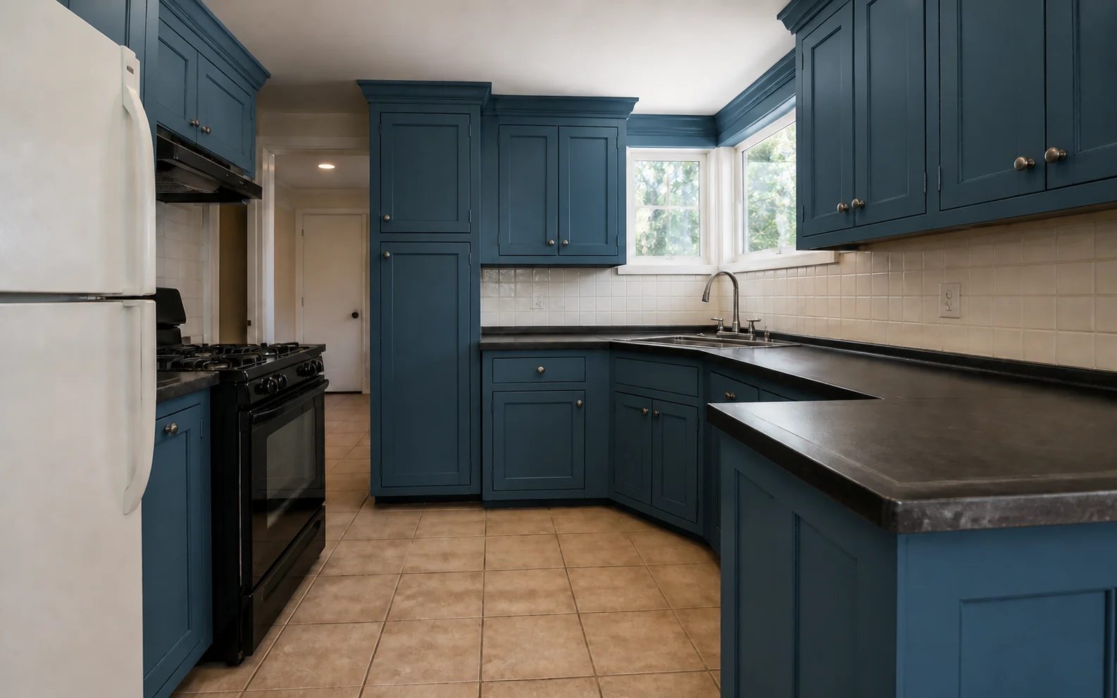 The same L-shaped kitchen with every cabinet repainted deep muted petrol blue